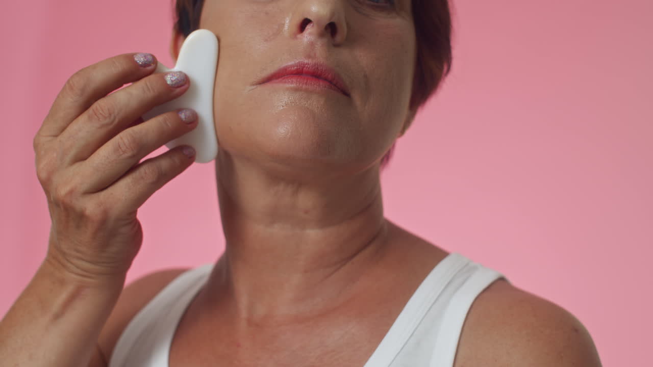 Mature Woman Doing Rejuvenation Cheeks Massage with Gua Sha