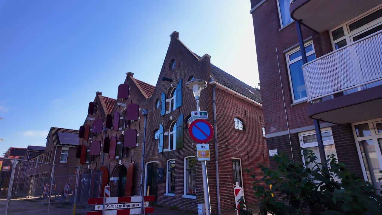 Old brick Dutch warehouses with red shutters aligned beside modern apartments on a sunny street. Location: Coevorden, Drenthe, Netherlands – Coevorden, Drenthe, Nederland