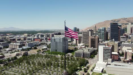 bandera patriótica estadounidense ondeando en el horizonte del centro de salt lake city en utah - aérea