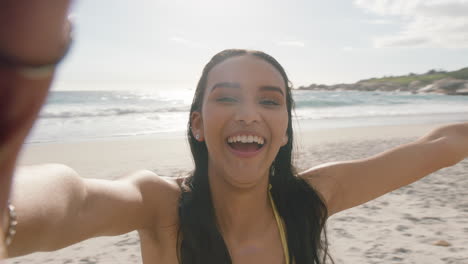 Joven-Mujer-De-Raza-Mixta-Teniendo-Video-Chat-En-La-Playa-Chica-Lanzando-Un-Beso-A-La-Cámara-Compartiendo-Vacaciones-De-Verano-Usando-Un-Teléfono-Inteligente-Mostrando-Aventuras-De-Viaje-Divirtiéndose-En-Vacaciones