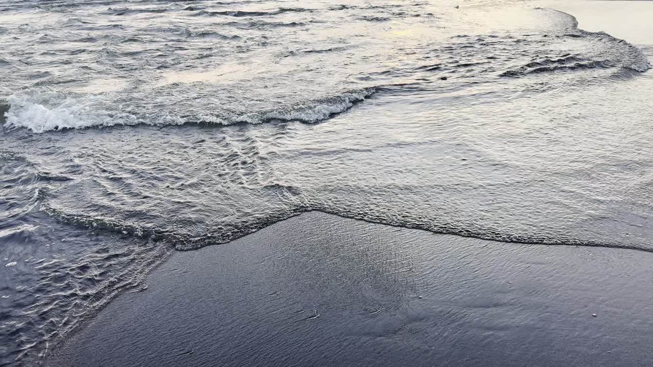 Gentle Ocean Waves Washing Ashore on a Dark Sandy Beach