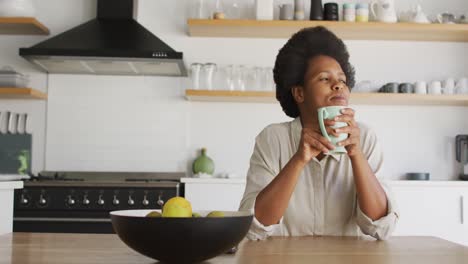 Glückliche-Afroamerikanische-Frau,-Die-Kaffee-In-Der-Küche-Trinkt