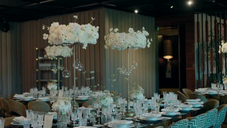 luxurious wedding table setup with tall white floral centerpieces and crystal details indoors