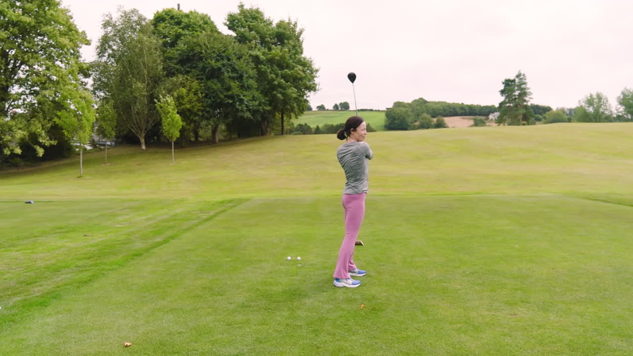 Two male and female golf players playing golf together, hitting the ball with club on a golf course
