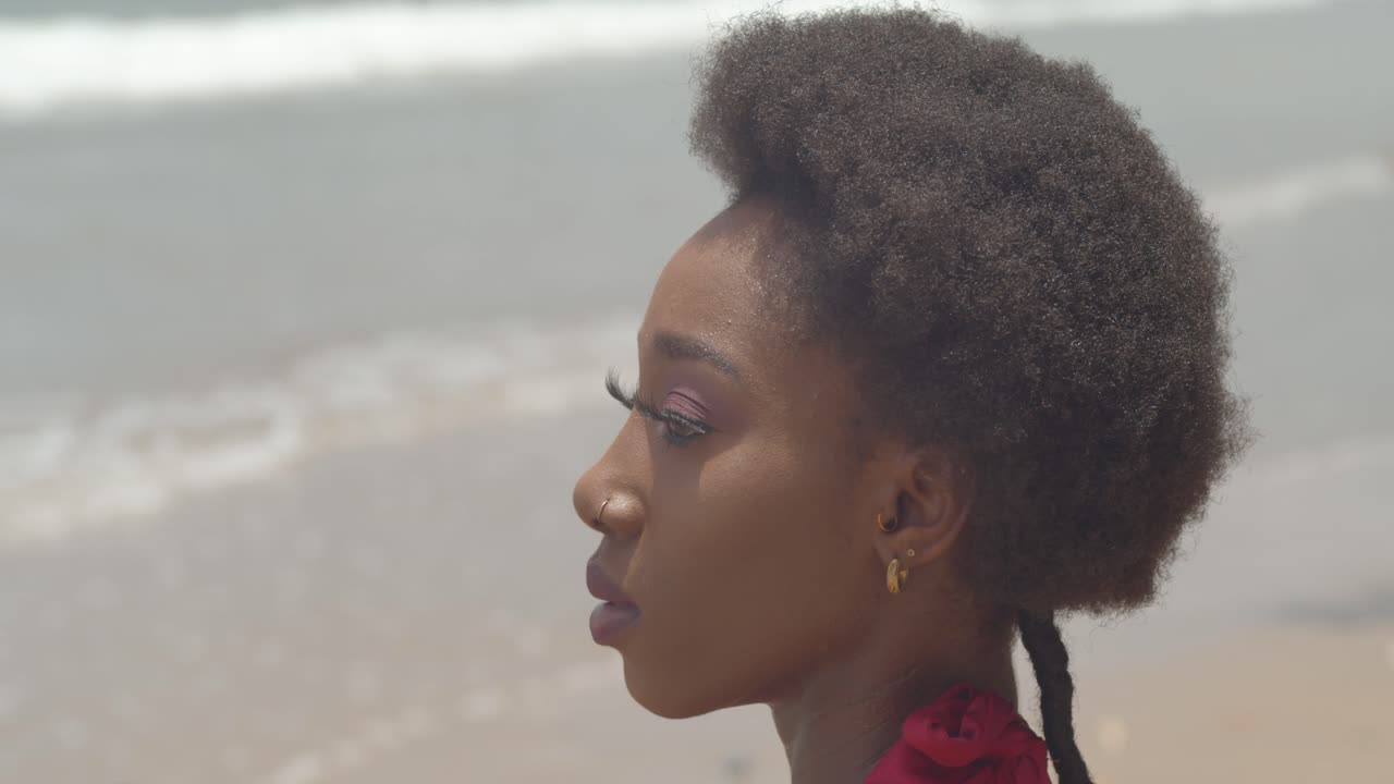 Primo piano di modella africana con acconciatura afro e onde dell'oceano sullo sfondo