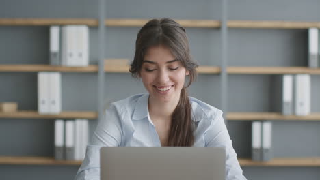 mujer mirando emocionada a la computadora portátil en la oficina