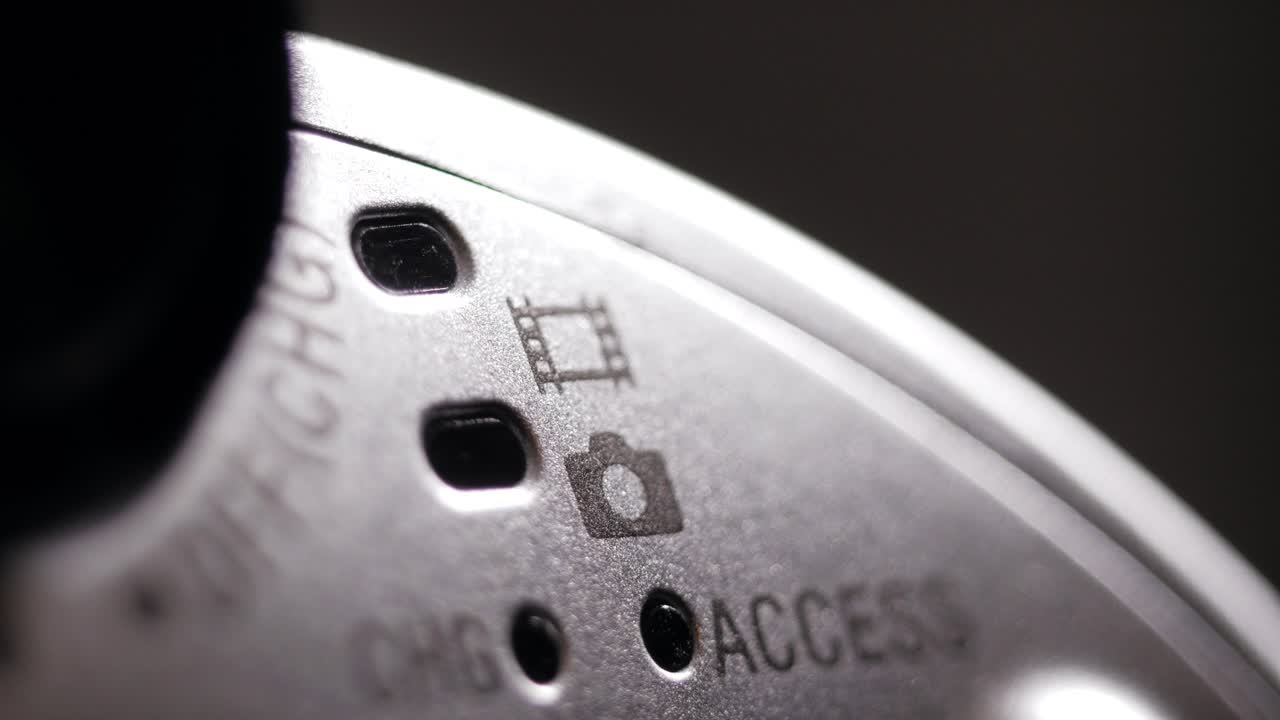 Macro rotating shot of silver camcorder body showing film and photo icons and access LED holes