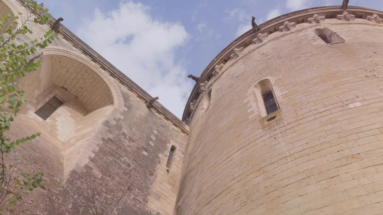 Archi in pietra di un edificio storico immersi nel verde sotto un cielo parzialmente nuvoloso ad Amboise.