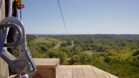 a young man glides out across the oklahoma treetops on a zip line