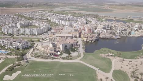 Drone-footage-of-La-Torre-Golf-Resort-in-Spain,-drone-flyine-over-golf-resort-and-lake-with-views-of-Murcia-Spain