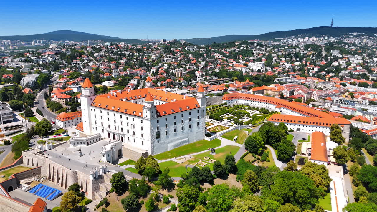 Approaching the building of the medieval Bratislava Castle. Green scenery of the city with landmark in the center. Aerial view