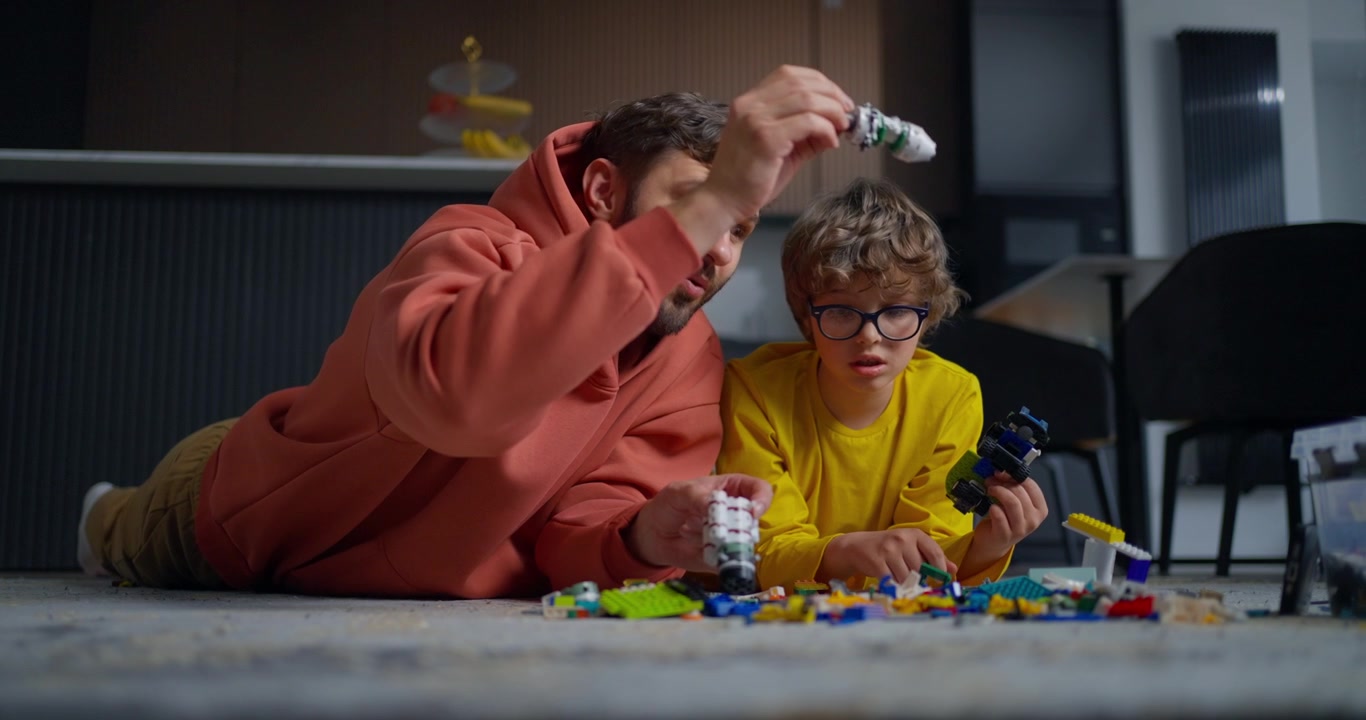 Happy Father and Son Playing with Lego Blocks on the Floor