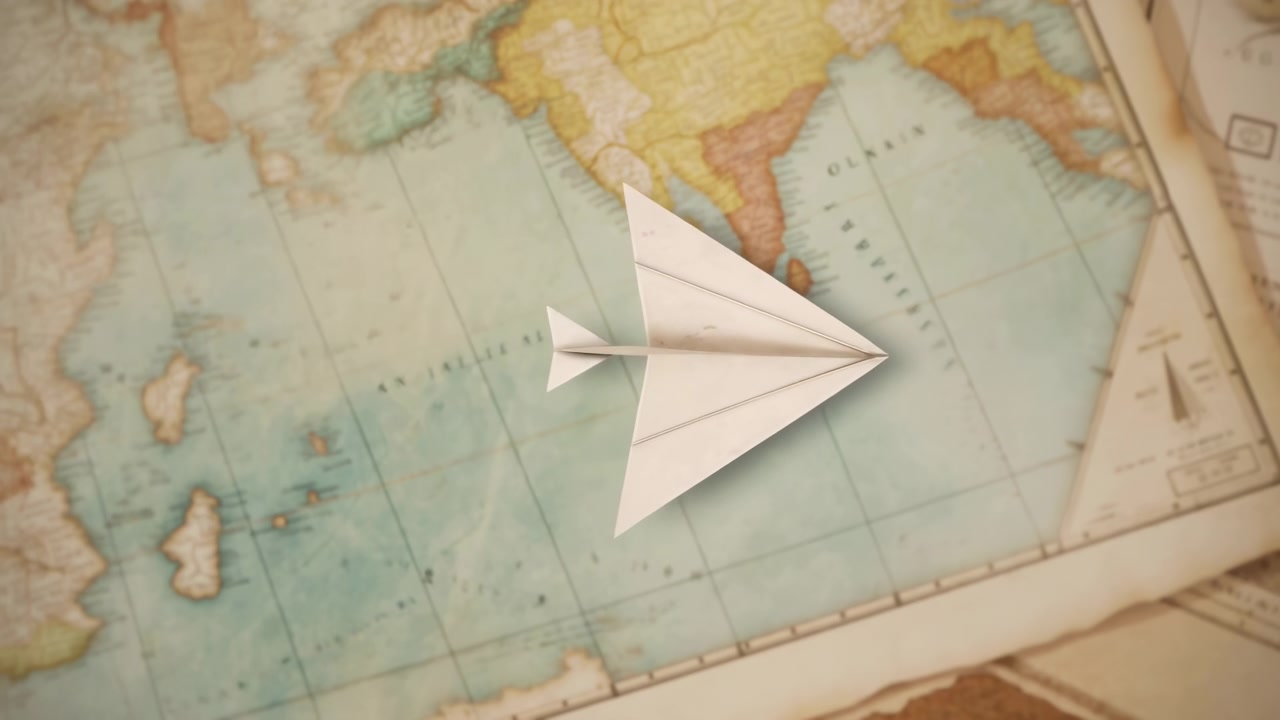 Um avião de papel dobrado move-se constantemente sobre a superfície de um mapa antigo da esquerda para a direita, cruzando um oceano azul-claro perto do Sudeste Asiático, enquanto uma iluminação quente e foco raso enquadram a cena.