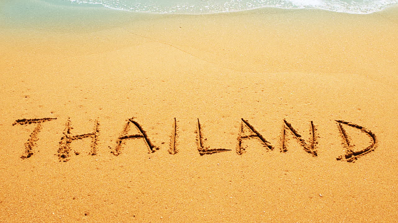 Inskription på sanden Thailand. Fotografering på stranden.