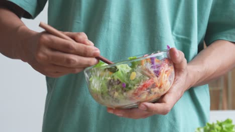 un hombre haciendo ensalada moviendo verduras frescas con mayonesa en el cuenco