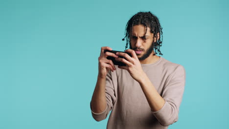 man nodding head, upset after losing videogame, playing on phone in studio