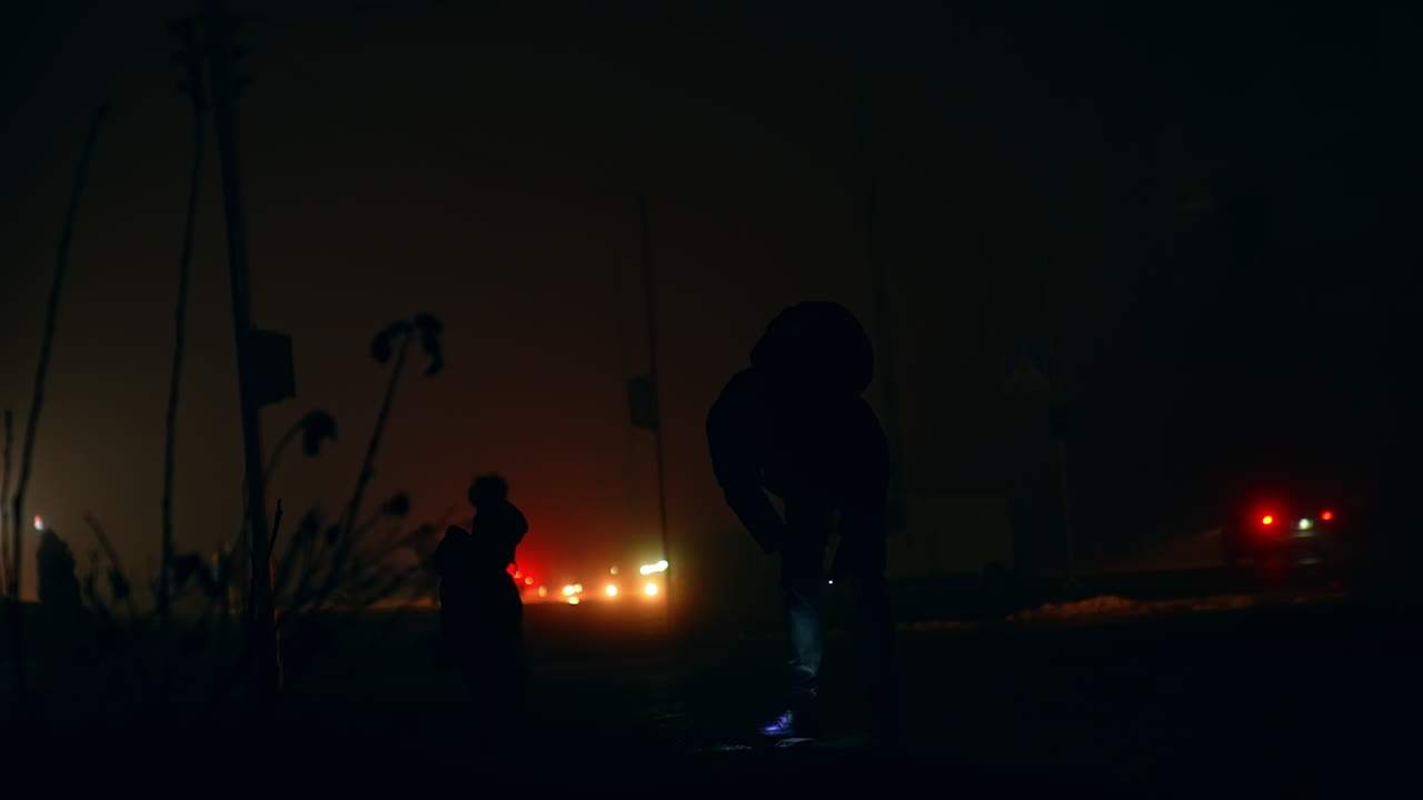 Silhouette of people walking at night in foggy city