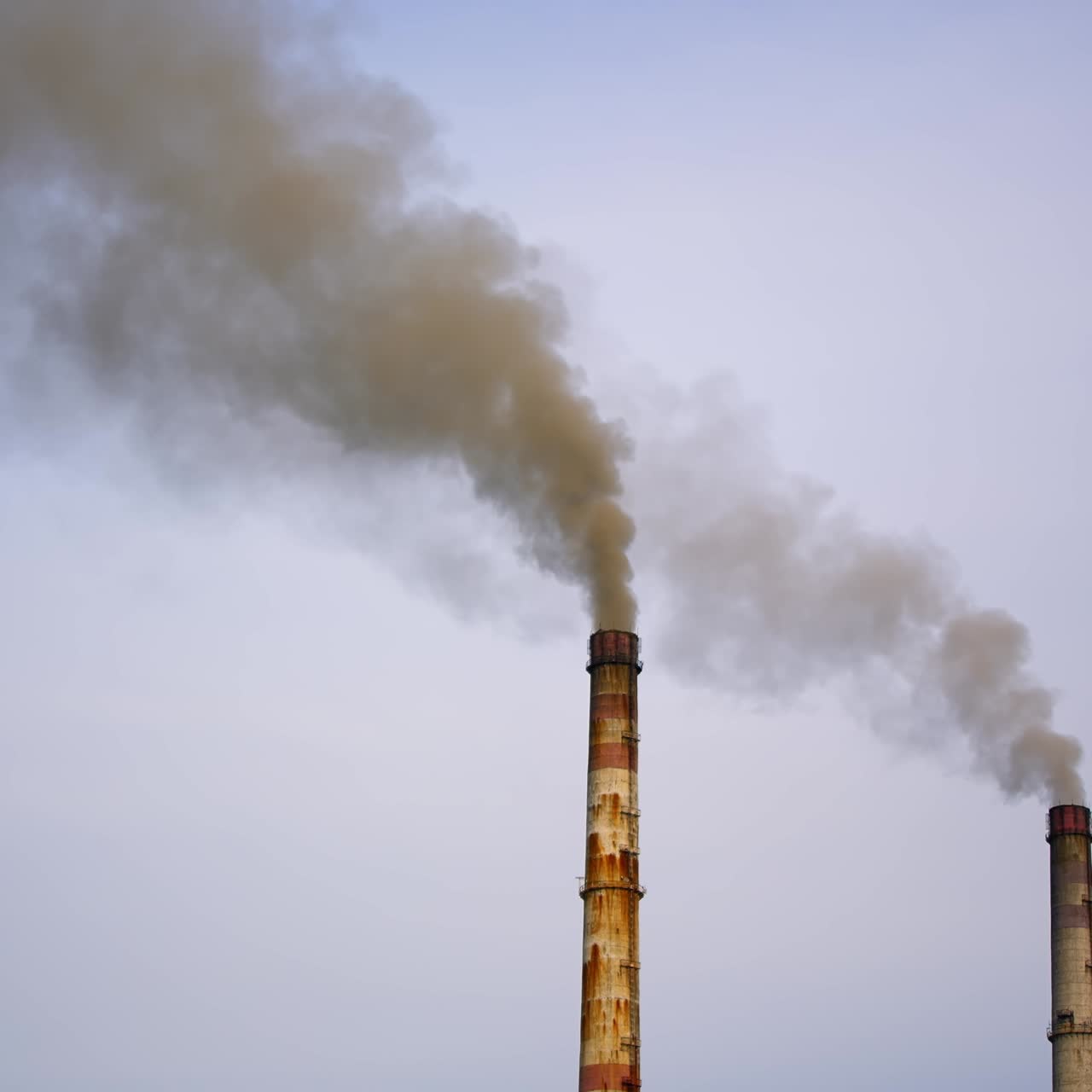 Factory pipes with smoke. Dirty smoke pours out of chimneys into the air on the river background. Aerial view video