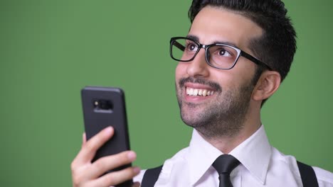 young handsome bearded persian businessman against green background