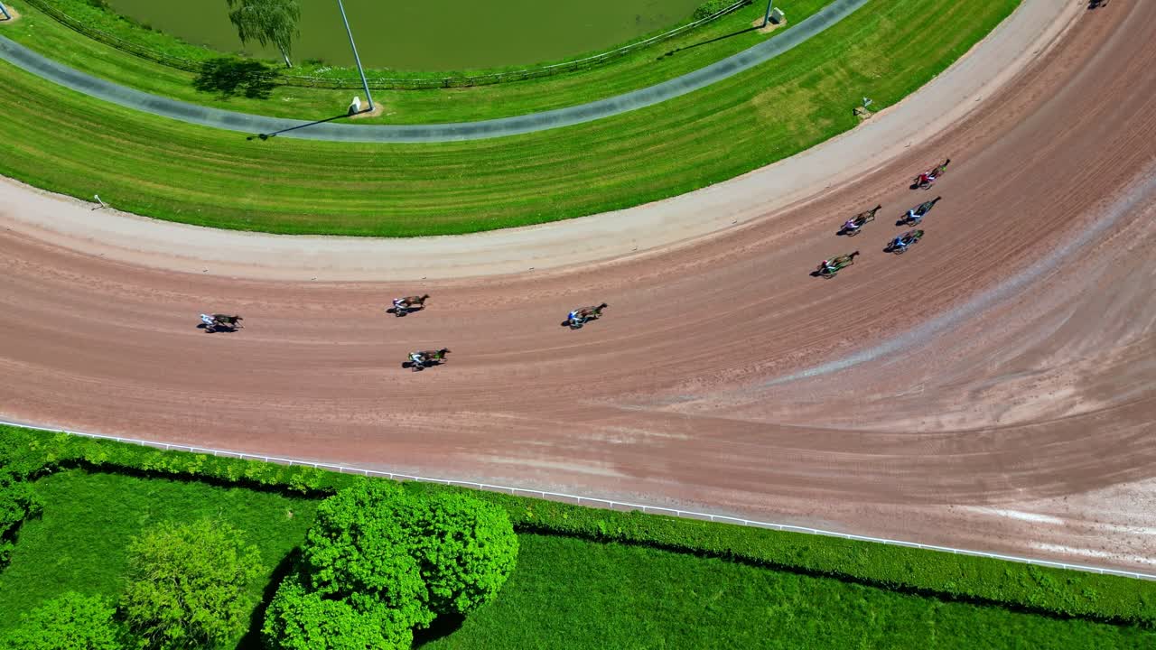 Amazing top-down drone view of a horse racing event on oval dirt hippodrome track amid green field, Laval, Mayenne, France.