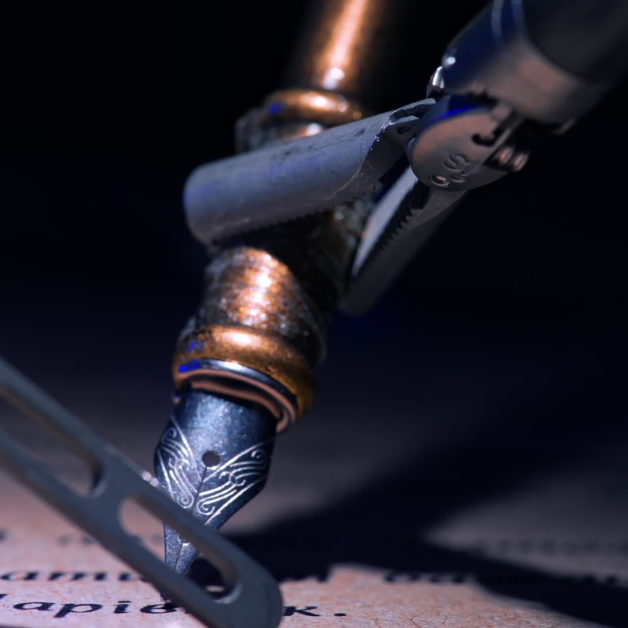 Tiny forceps of robotic arm hold the old-fashioned writing pen. Close up. Da Vinci performs writing in dark surgical room