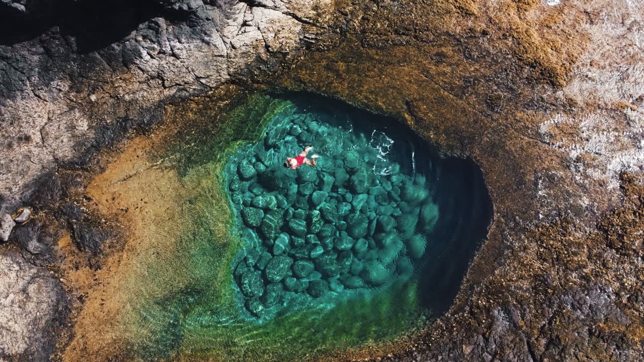 Una donna in costume da bagno rosso sta nuotando in una caletta vicino a Caleta de Fuste