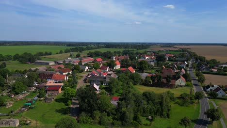 idyllic scenery of tarmow, a small village nestled amidst vast agricultural fields in brandenburg, germany, on a sunny summer day. panorama orbit drone