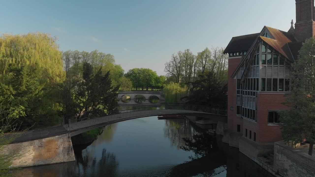 Sunny and clear day in Cambridge city, England. There is a bridge over the river for pedestrians
