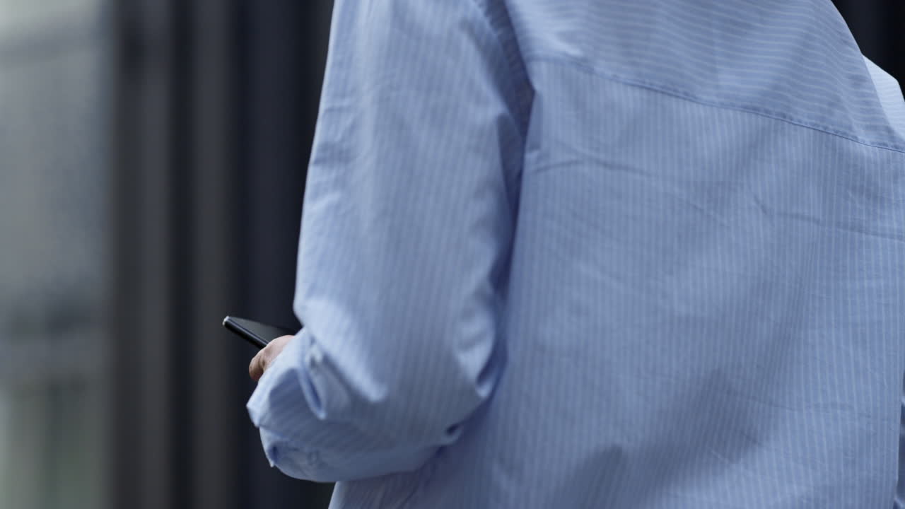 Primo piano di mani che tengono uno smartphone in centro città. Social networking all'aperto.