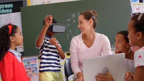 vista frontal de un escolar afroamericano usando auriculares de realidad virtual con el maestro y sus compañeros de clase