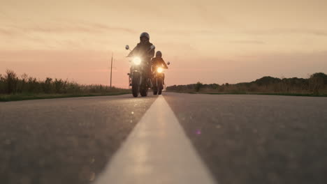 Two-motorcycles-drive-on-a-flat-highway-at-sunset-1