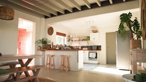 cozy kitchen with wooden stools and plants, sunlight streaming through window, copy space