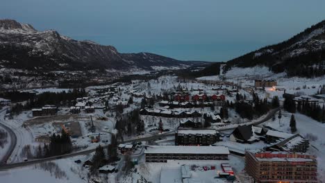 late evening aerial in hemsedal norway - loads of leisure homes and apartment building under construction in foreground - ascending aerial from skiing location during dusk hours revealing full valley