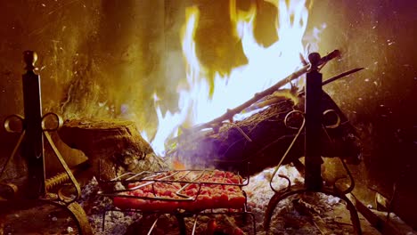 Sausages-cooking-on-fireplace-grill-with-fire-burning-in-background,-Close-up