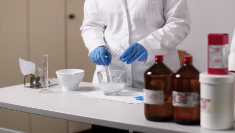 Slow-Motion-Shot-of-an-medical-assistent-mixing-a-liquid-and-a-cream-in-a-glass-bowl