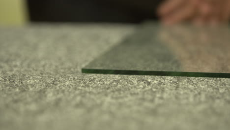 cutting off a small piece of a big glass panel on a working table