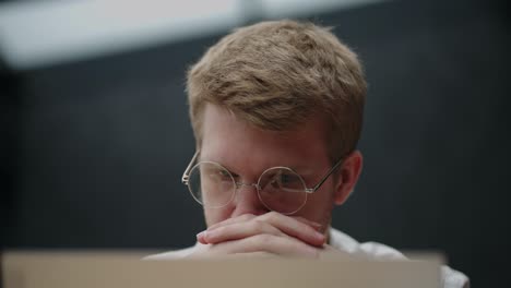 retrato de un hombre cansado y pensativo mirando la pantalla de una computadora portátil con gafas. un hombre de lluvia de ideas. resolución de problemas. pensar y trabajar