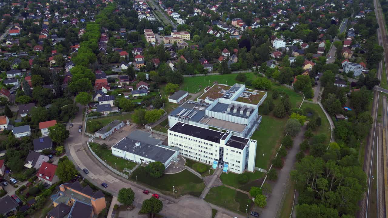 datacenter building with cooling system on the roof, surrounded by residential houses, showcasing urban and industrial integration. drone camera pointing down