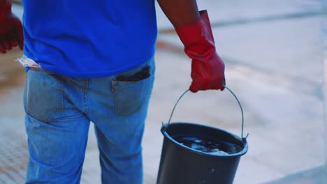 male worker with rubber gloves carrying a bucket with acid for pool cleaning - close up