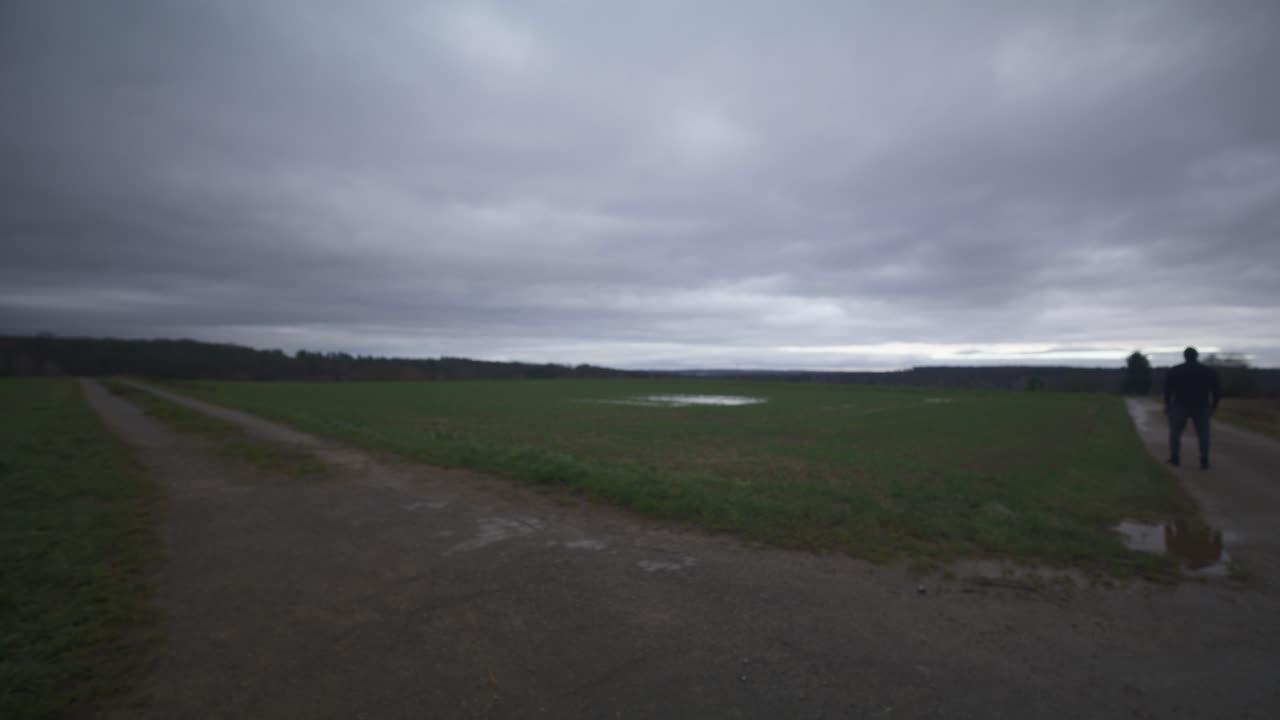 현대의 검은 검사 전사는 회색 하늘 아래 야외에서 대결 상대를 기다리고 있습니다 - 유럽, 4k - 근육, 협박, 그림자, 형상, 흐릿한, 어두운 옷, 강력한, 멀리 서, 돌아서십시오.