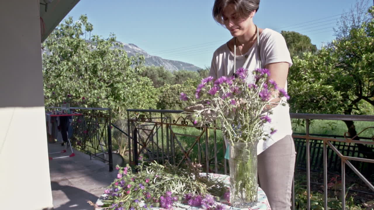 mujer decora un vaze con flores silvestres en el porche de una casa de campo 60fps