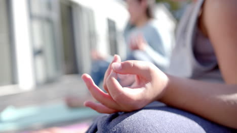 Happy-biracial-mother-and-daughter-practising-yoga-on-terrace-in-sunny-day,-slow-motion