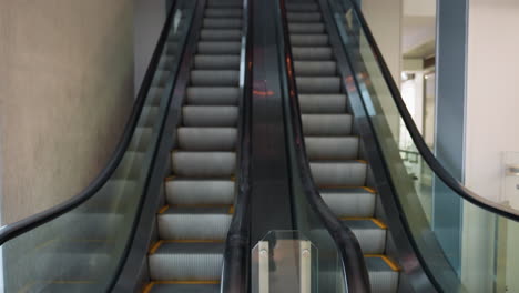 two escalators, one going up and the other coming down, in a modern indoor setting. the camera focuses on the symmetry and functionality of the escalators, highlighting the sleek design and usage