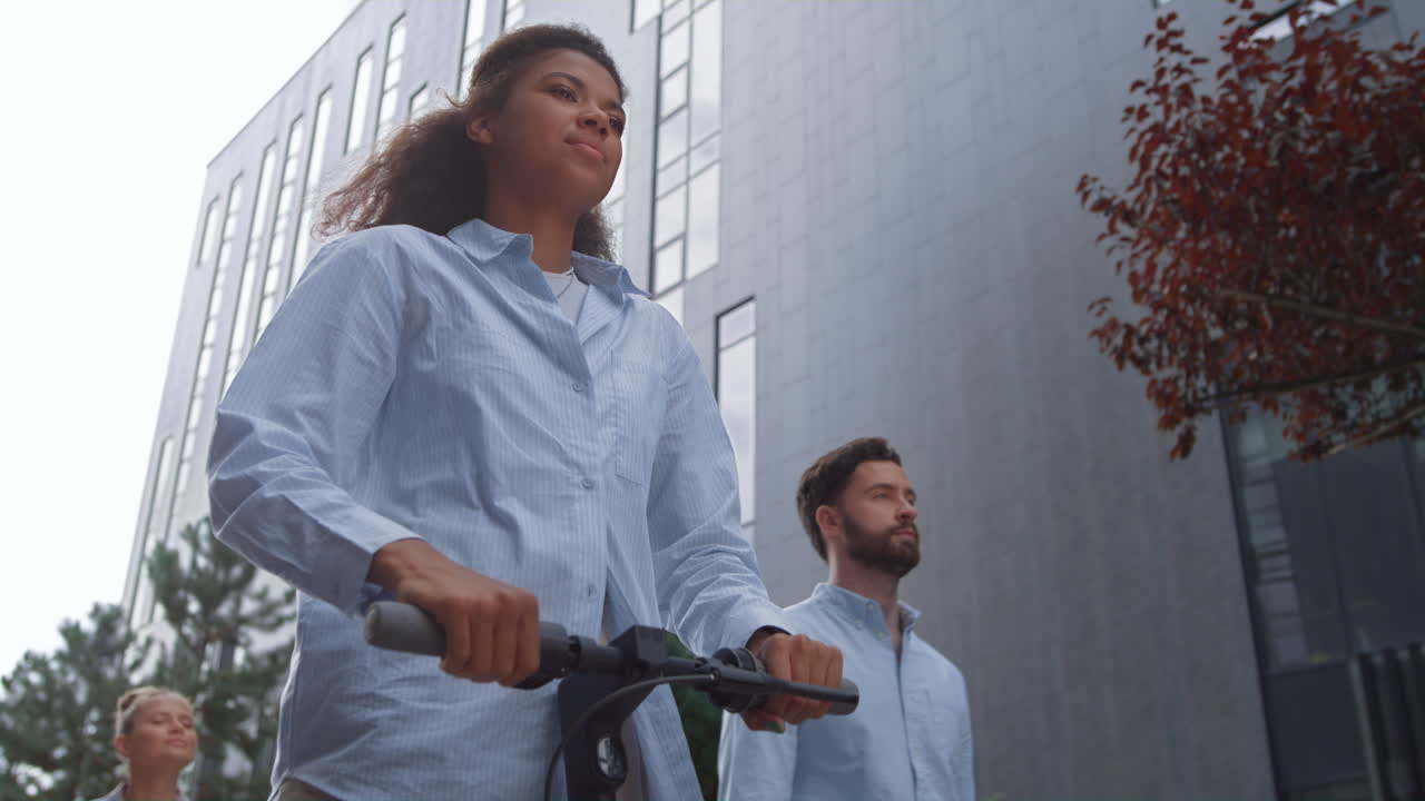 Attractive businesswoman riding electric scooter in downtown district going away