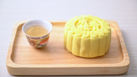 Chinese-moon-cake-custard-flavour-with-tea-on-wood-plate