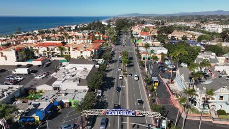 Movimiento-Aéreo-Hacia-Atrás-Disparado-Sobre-La-Carretera-De-La-Costa-Pacífica-Con-La-Ciudad-Bien-Planificada-De-Carlsbad-En-California,-Ee.uu.-Con-La-Vista-Del-Océano-En-El-Fondo