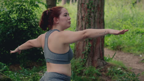 girl practices yoga in a forest warrior move