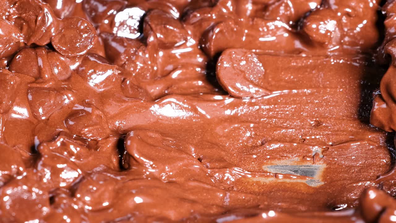 Close-up view of a spoon stirring smooth, melted chocolate chips.