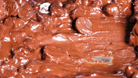 close-up view of a spoon stirring smooth, melted chocolate chips.