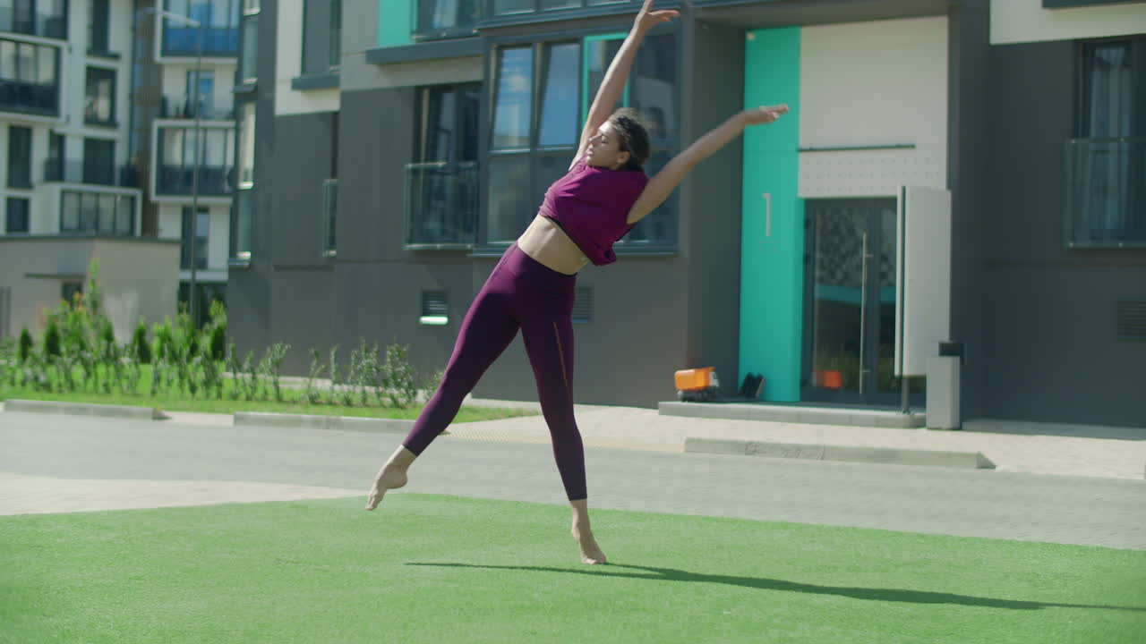 Woman doing acrobatic exercise outside apartment building